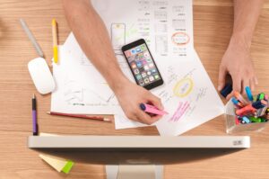 Person writing on white paper with a pen, representing planning or strategy development for brand recognition and SEO success.